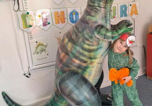 Dziewczynka pozuje do zdjęcia z dmuchanym dinozaurem