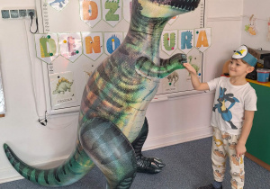 Chłopiec pozuje do zdjęcia z dmuchanym dinozaurem