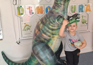 Chłopiec pozuje do zdjęcia z dmuchanym dinozaurem