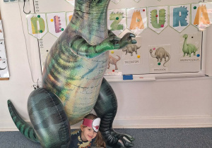 Dziewczynka pozuje do zdjęcia z dmuchanym dinozaurem