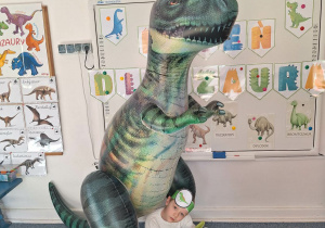 Chłopiec pozuje do zdjęcia z dmuchanym dinozaurem