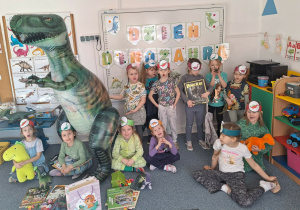 Grupa dziewczynek pozuje do zdjęcia z dmuchanym dinozaurem