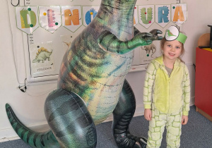 Dziewczynka pozuje do zdjęcia z dmuchanym dinozaurem