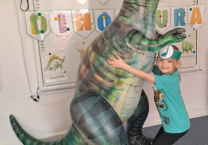 Dziewczynka pozuje do zdjęcia z dmuchanym dinozaurem