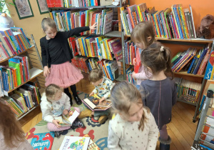 Grupa dzieci ogląda książki w kąciku czytelniczym
