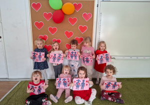 Dzieci pozują do zdjęcia trzymając wykonane przez siebie walentynki