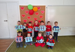 Dzieci pozują do zdjęcia trzymając wykonane przez siebie walentynki