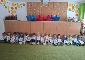 Dzieci pozują do zdjęcia trzymając wykonane prze siebie prace