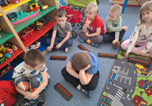 Grupa dzieci siedzi na dywanie i ćwiczy na własnym liczydle