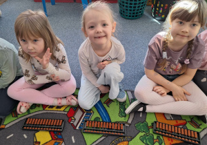 Grupa dzieci siedzi na dywanie i ćwiczy na własnym liczydle