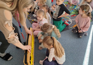 Grupa dzieci siedzi na dywanie i ogląda liczydło