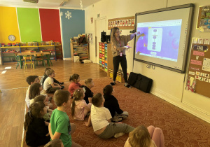 Pani pokazuje prezentacje na tablicy multimedialnej grupie dzieci