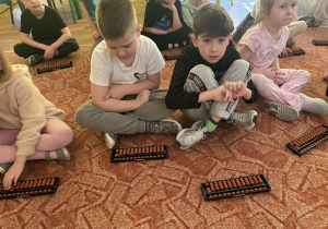 Dzieci siedzą przed liczydłami zwanymi abakus