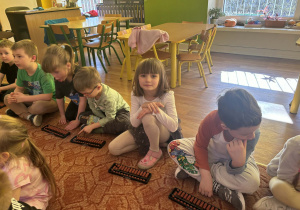 Dzieci siedzą przed liczydłami zwanymi abakus