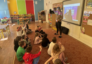 Pani pokazuje prezentacje na tablicy multimedialnej grupie dzieci