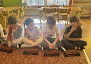 Dzieci siedzą przed liczydłami zwanymi abakus