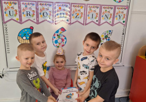 Grupa dzieci składa Nadii urodzinowy dyplom