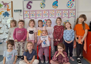 Dziewczynki stoją na dywanie i pozują z Nadią do zdjęcia na tle urodzinowej dekoracji