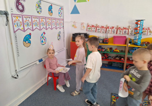 Grupa dzieci składa dziewczynce siedzącej na krześle życzenia