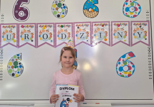 Michalina stoi na tle urodzinowej dekoracji