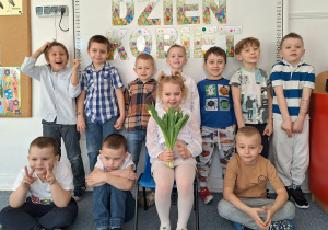 Dziewczynka pozuje do zdjęcia z chłopcami na tle dekoracji