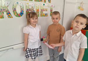 Dwóch chłopców wręcz dziewczynce upominek