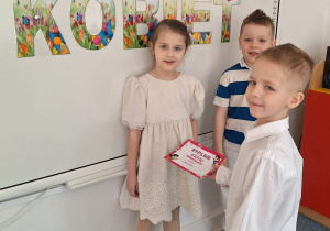 Dwóch chłopców wręcz dziewczynce upominek