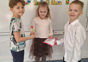 Dwóch chłopców wręcz dziewczynce upominek