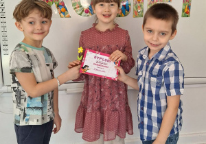 Dwóch chłopców wręcz dziewczynce upominek