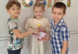 Dwóch chłopców wręcz dziewczynce upominek