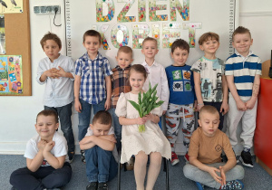 Dziewczynka pozuje do zdjęcia z chłopcami na tle dekoracji