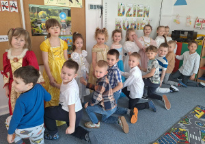 Chłopcy klęczą przed dziewczynkami ubranymi w stroje balowe