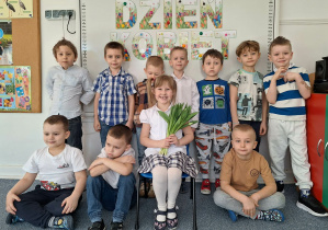 Dziewczynka pozuje do zdjęcia z chłopcami na tle dekoracji