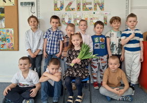 Dziewczynka pozuje do zdjęcia z chłopcami na tle dekoracji