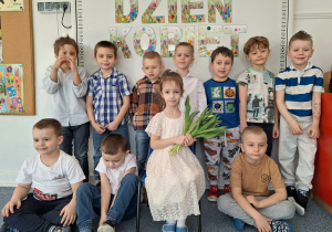 Dziewczynka pozuje do zdjęcia z chłopcami na tle dekoracji