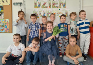 Dziewczynka pozuje do zdjęcia z chłopcami na tle dekoracji