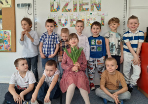 Dziewczynka pozuje do zdjęcia z chłopcami na tle dekoracji