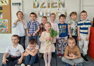 Dziewczynka pozuje do zdjęcia z chłopcami na tle dekoracji