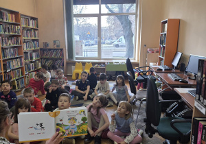 Dzieci słuchają jak Pani bibliotekarka czyta książkę