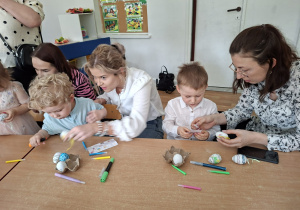 Dzieci wspólnie z rodzicami ozdabiają pisanki