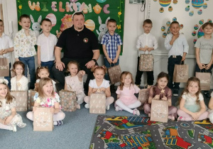 Dzieci siedzą na dywanie ipozują do zdjęcia z prezentami od wielkanocnego króliczka