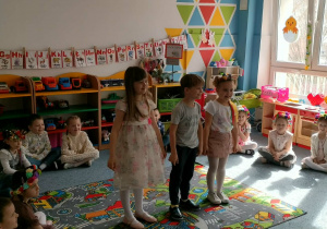 Trójka dzieci stoi na dywanie i recytuje wiersz