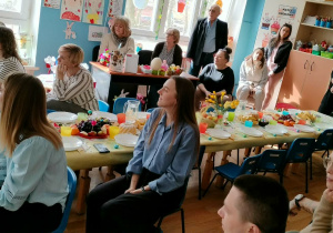 Rodzice siedzą na krzesłach i ogląda uroczystość