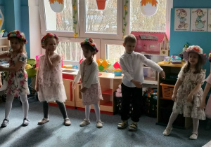 Grupa dzieci stoi na dywanie i śpiewa piosenkę