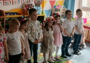 Grupa dzieci stoi na dywanie i recytuje wiersz