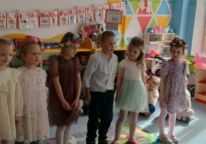 Grupa dzieci stoi na dywanie i recytuje wiersz