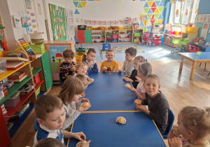 Dzieci siedzą przy stole i jedzą urodzinowe babeczki