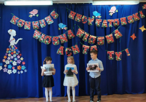 troje dzieci stoi z obrazkami w dłoniach