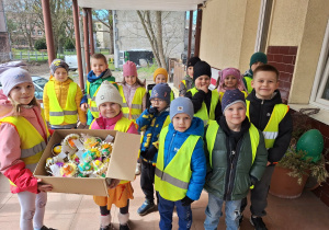 Grupa dzieci z ozdobami świątecznymi przed DPS-em