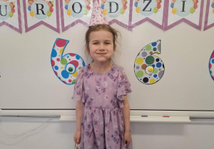Ania stoi na tle dekoracji urodzinowej i pozuje do zdjęcia